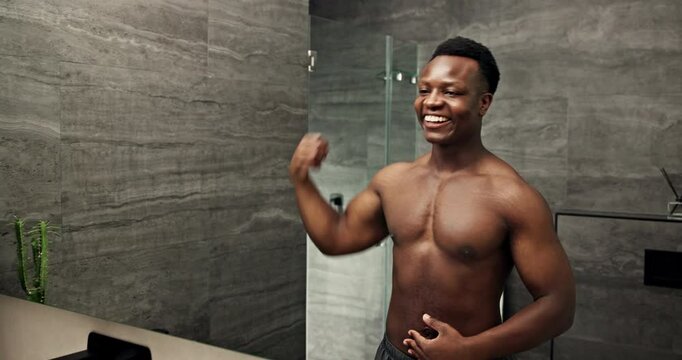 Black man, mirror and muscle flex in bathroom for fitness, results and confidence with progress and abs in home. African person, reflection and strong body for exercise, bicep power and wellness