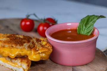 A grilled Cheese sandwich with a side of tomato soup. The sandwich is cut in half and the cheese is melted