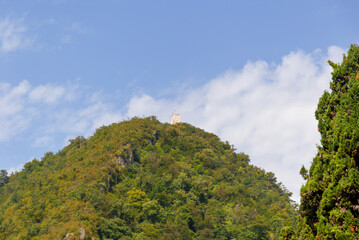 Obraz premium Scenic view of the mountain with a monument among the trees against the background of the blu