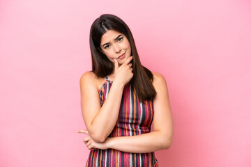 Young Brazilian woman isolated on pink background having doubts