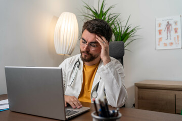 Overworked doctor in his office. An overworked doctor sits in his cluttered office, surrounded by...
