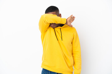 Young latin man isolated on white background covering eyes by hands