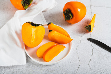 Plate with pieces of sweet tasty persimmon on white background