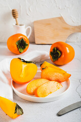 Sliced ​​ripe fresh persimmon on a plate on a table vertical view