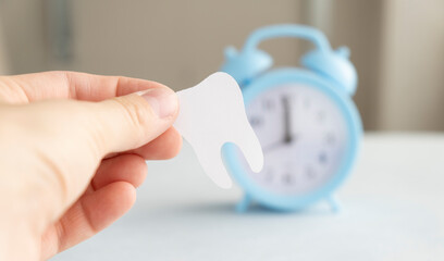 Tooth figurine in hand on blue background. Means to care for the oral cavity.