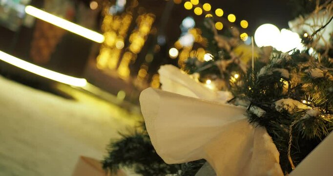 Holiday season. The Christmas tree is decorated with toys and burning garlands on the background of the facade of the building. Camera rotation. Hand held. Siberia. Bokeh.
