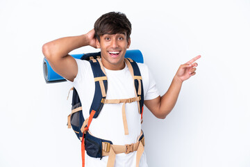 Young mountaineer woman with a big backpack over isolated white background surprised and pointing finger to the side