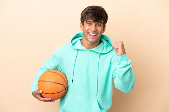 Handsome young basketball player man isolated on ocher background celebrating a victory in winner position