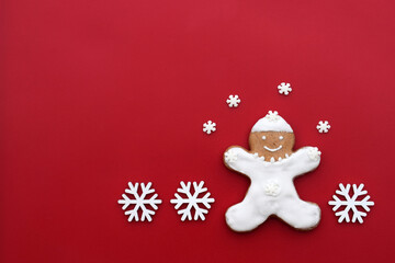 Smiling gingerbread man on a red background with snowflakes around, copy space for text. Christmas time