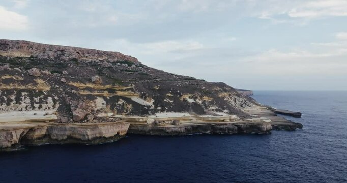 Aerial view of the rocky precipitous coast of the sea on the island of Malta. The waves of the Mediterranean Sea crash on the shore. High quality 4k footage
