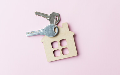 Mini house figurine with keys on an pink desk.