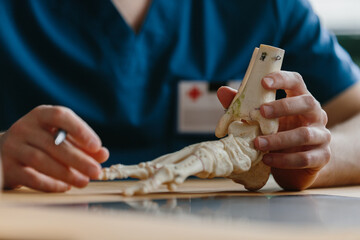 Close-up of a doctor explaining foot anatomy with a model.