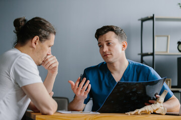Physician presenting an X-ray to a patient while explaining the results.