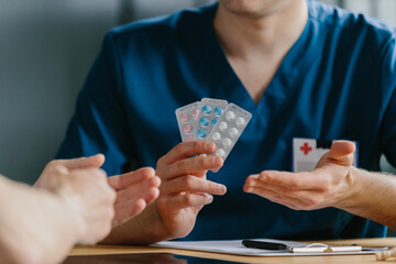 Close-up of doctor providing three blister packs of medication to a patient.