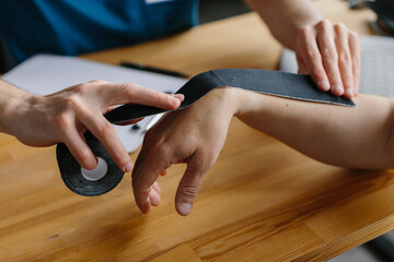 Physician preparing kinesiology tape for arm treatment on a patient. Close up.