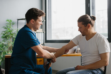 Physician preparing kinesiology tape for arm treatment on a patient.