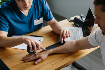 Physician preparing kinesiology tape for arm treatment on a patient. Close up.