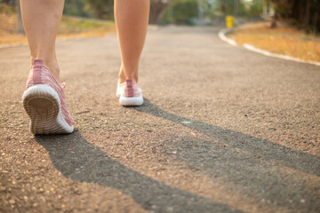 young woman wearing a sports outfit and sneakers walks along the path ahead towards her intended destination. young woman walks forward with determination towards her goal with her two feet.