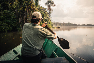 Explorer paddling a canoe on the amazon river at sunset
