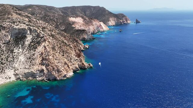 Aerial drone cinematic video of paradise blue bay of uninhabited island of Polyaigos with turquoise crystal clear sea visited by luxury yachts and sail boats resembling a blue lagoon, Cyclades, Greece
