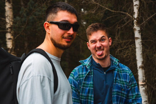Two men in sunglasses and plaid shirts are making funny faces