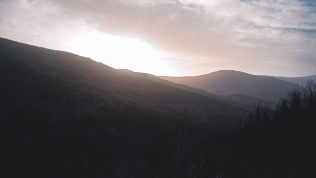 The sun shines beautifully through clouds over majestic mountains