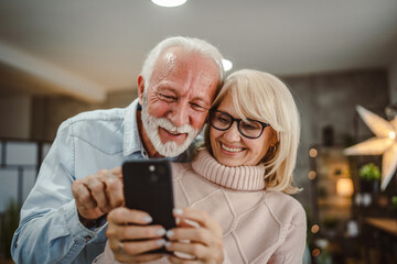 senior couple husband and wife have fun while use mobile phone at home