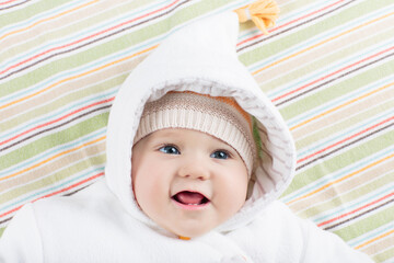 Little baby in winter hat on white bed