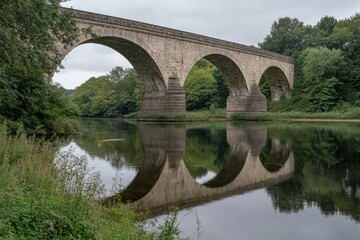 Fototapeta premium Stone Arch Bridge Reflecting in Calm River Water