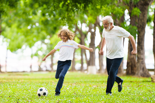 Grandfather and kids play football in summer park