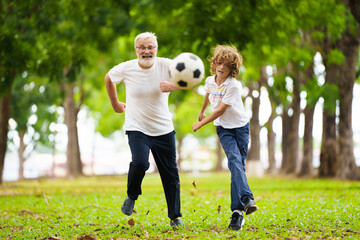 Grandfather and kids play football in summer park