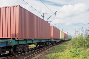 Fototapeta premium Freight transport: a train of flatcars carrying containers travels along the railway