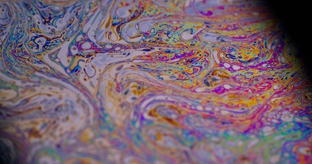 Abstract liquid. Bubble decoration. Defocused multicolor purple green oil paint curve acrylic slick on dark black blurred light art background.