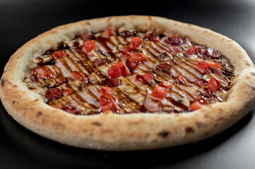 details of the pizza application; juicy pizza from the oven with mushrooms, tomatoes and bacon and sprinkled with parmesan cheese