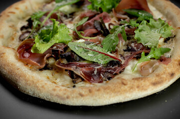 details of the pizza application; juicy pizza from the oven with mushrooms, tomatoes and bacon and sprinkled with parmesan cheese