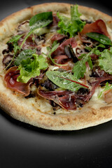 details of the pizza application; juicy pizza from the oven with mushrooms, tomatoes and bacon and sprinkled with parmesan cheese