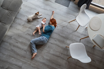 Top view of caucasian woman lying on floor with newborn son and jack russell terrier dog. 