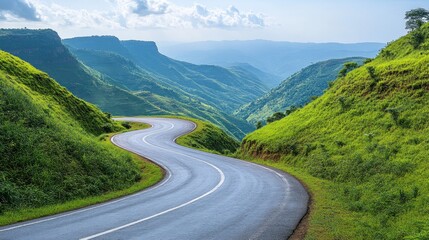 Fototapeta premium Winding mountain road through lush green valley.