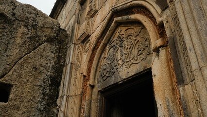 An ancient doorway featuring intricate and detailed carvings, surrounded by impressive natural rock formations