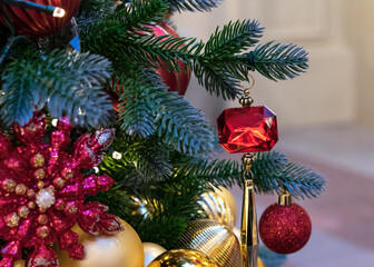 Christmas decoration in the shape of a red crystal with a gold pendant.