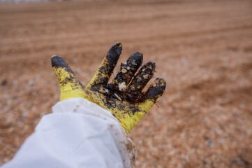 A volunteer's hand in a glove and in fuel oil against the background of the black sea. Stop the...