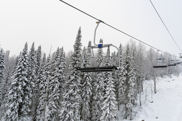 Empty ski chairlift in the middle of a forest in the mountains.