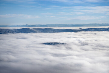View from the top of a mountain of a foggy valley in the mountains above the clouds.