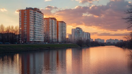 Obraz premium Sunset Cityscape with Apartment Buildings and River Reflection