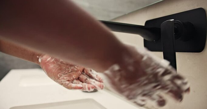 Person, hands and soap with water or faucet for hygiene, anti bacteria or sanitary cleanse in bathroom at home. Closeup, hygienist or washing palms with disinfectant, scrub or sink for germ removal