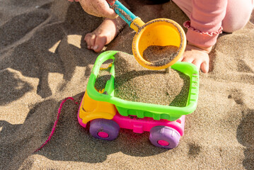 Child playing yellow sand on beach, kid in sandbox, close up hand
