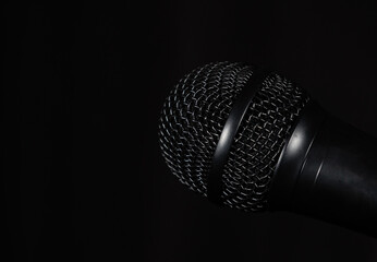 Black hand microphone capsule on black background. Concept: Podcasting, audiovisual technology, podcast, microphones.