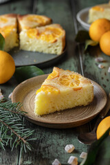 Upside down orange tangerine cake or pie slice on a plate on green wooden background. Fruit citrus pastry. Homemade winter baking
