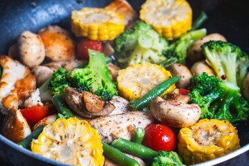 Background with vegetable texture. Corn, broccoli, mushrooms and green beans are fried in a pan. Close-up. The concept of healthy eating.