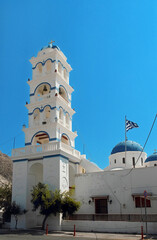 The church of Holy Cross in Perissa with the Greek flag. Greek Orthodox Church in Perissa, Santorini. Santorini Island, Greece.